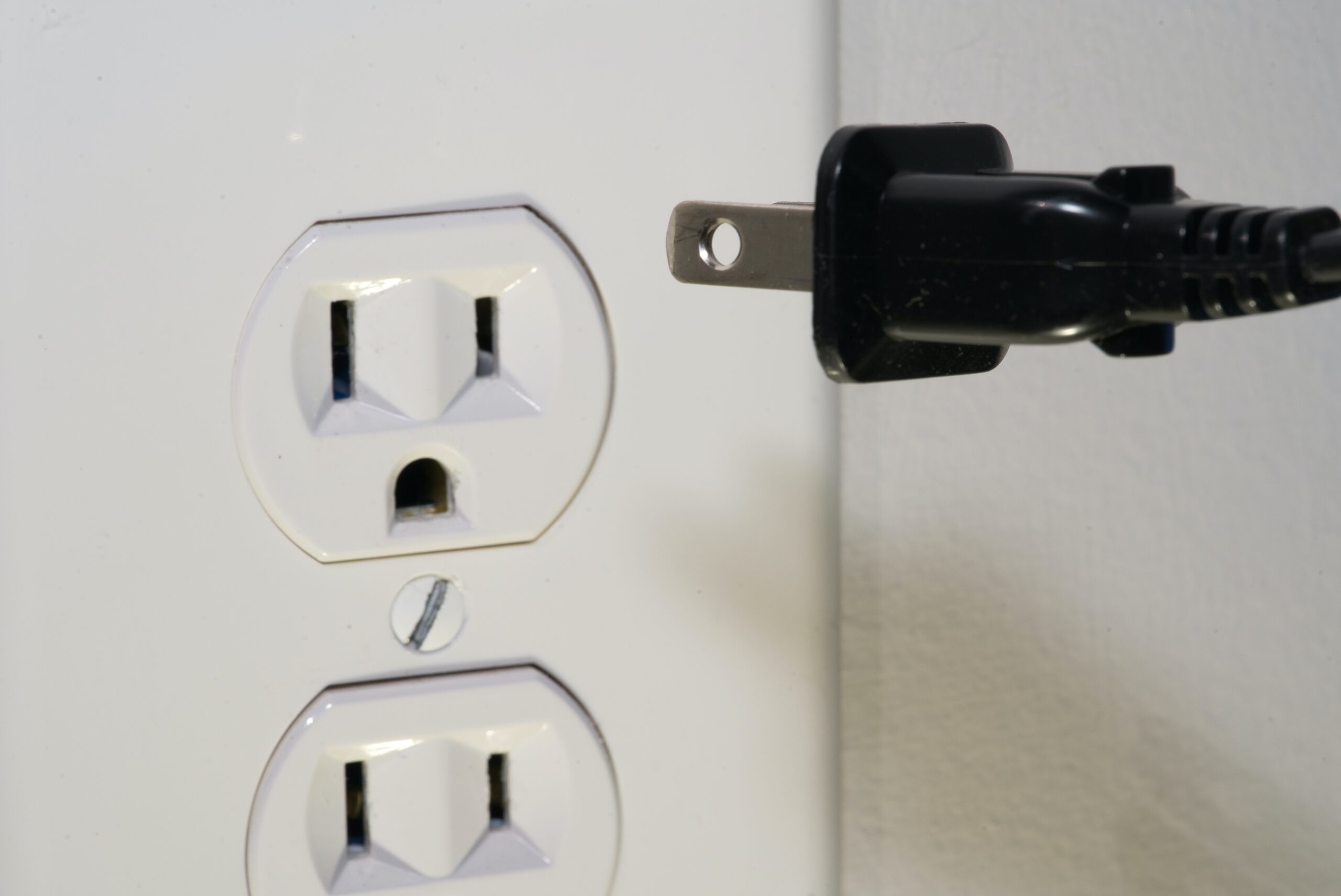 black male plug in front of electric socket scaled